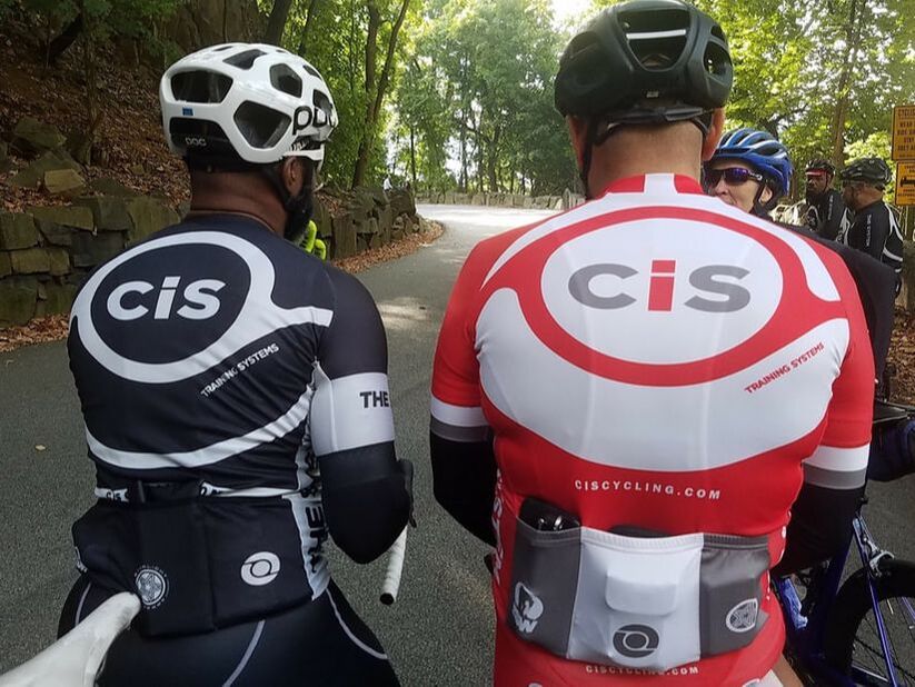 Two CIS Training Systems athletes standing back to back showing the Black Cycling Kit and Red Cycling Kit wth CIS Logo on the back.
